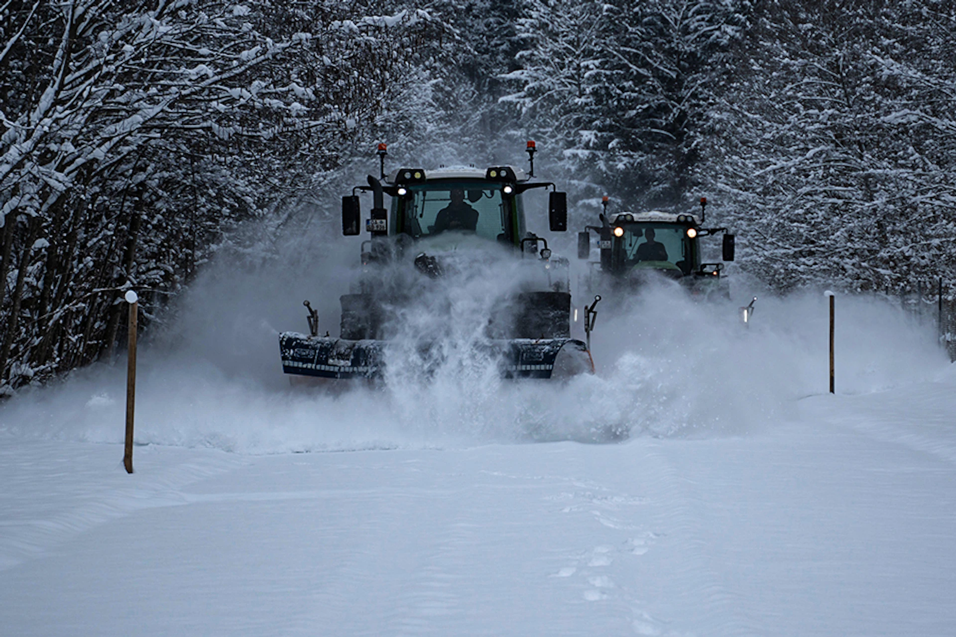 Schneeräum-Traktor fährt durch ein beschneites Waldstück und räumt den Schnee weg