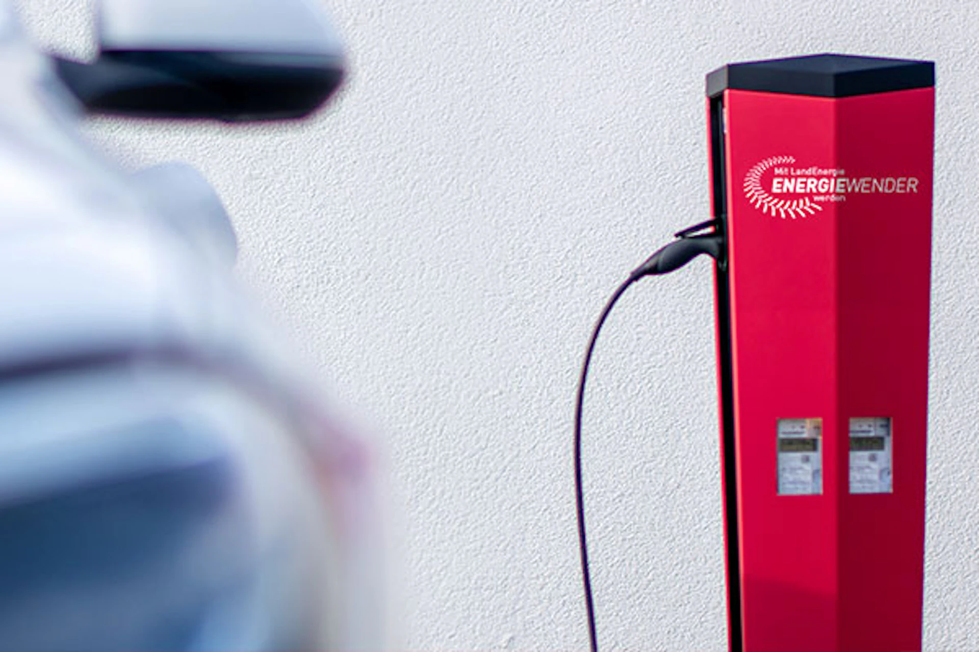 Auto ist an Ladesäule angeschlossen. Auf der Ladesäule ist das Energiewender Logo von LandEnergie