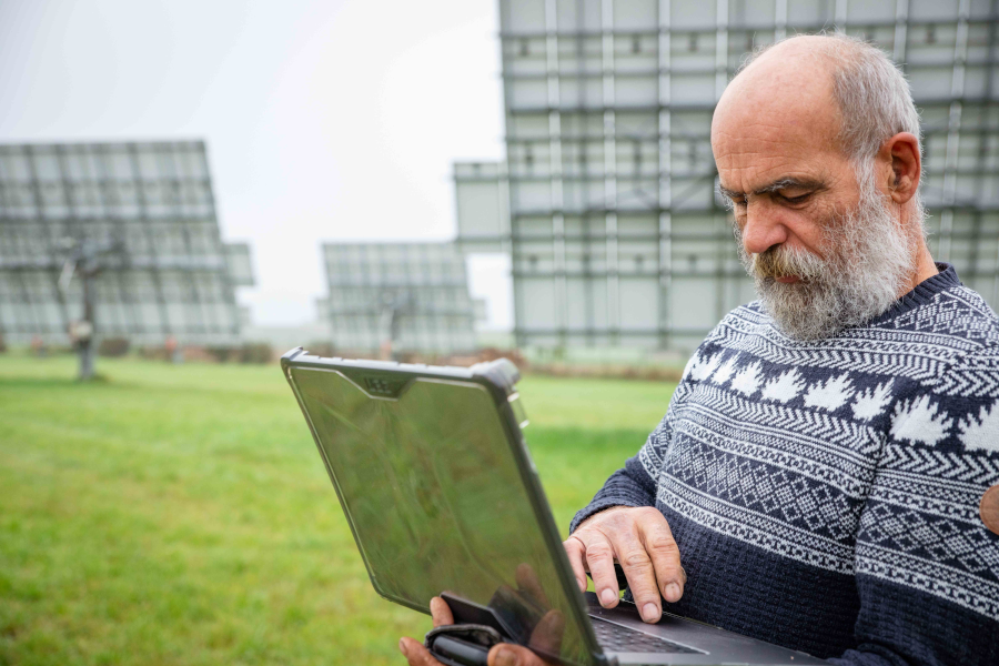 Landwirt mit Laptop auf einem Feld mit Solarpanele