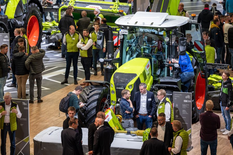 Besucher der Agritechnica besichtigen in einer Messehalle einen Claas-Traktor.