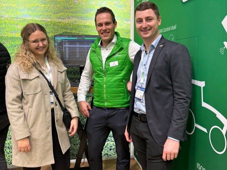 Eine Frau und zwei Männer vor einem Messestand