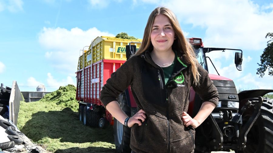 Betriebshelferin Anne Bühler steht vor einem Traktor mit Ladewagen.